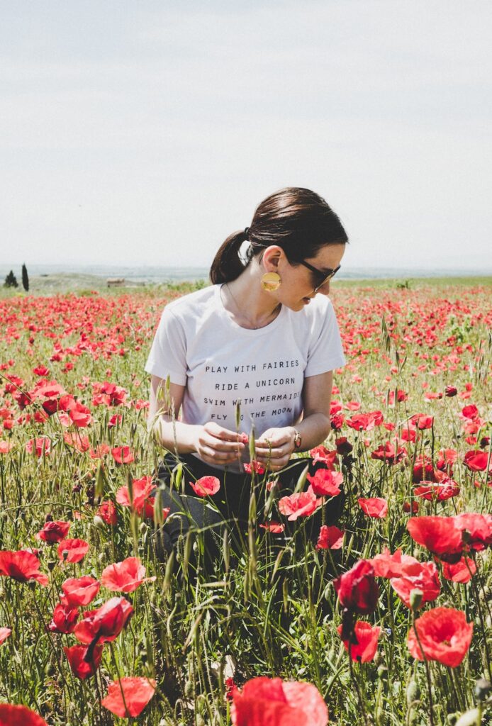 woman sitting on common poppy field