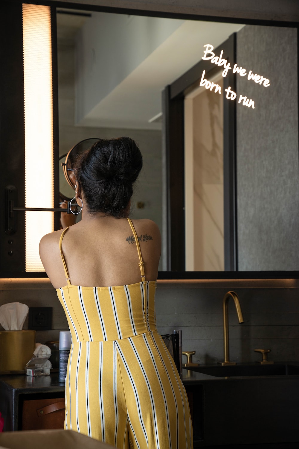 woman wearing yellow spaghetti strap jumpsuit near mirror