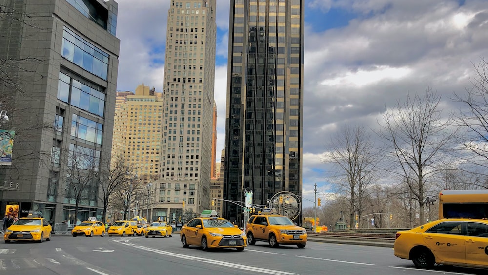 yellow car on road near high rise buildings during daytime